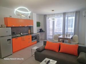 a living room with a couch and a kitchen with orange cabinets at Aglaya 2 in Pomorie