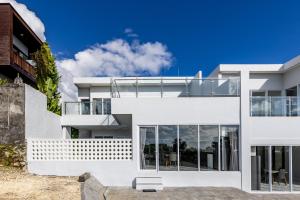 a white house with large glass windows at The Hill Ocean View Villa - Jimbaran Bali in Uluwatu