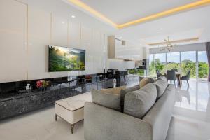 a living room with a couch and a tv on a wall at The Hill Ocean View Villa - Jimbaran Bali in Uluwatu