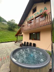 a building with a hot tub in front of a house at Casa de vacanța Tara in Rau Sadului