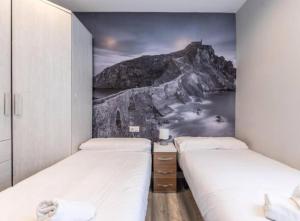 two beds in a room with a mountain mural at La Bondad apartamento in Barakaldo