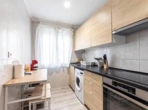 a kitchen with wooden cabinets and a washer and dryer at La Bondad apartamento in Barakaldo