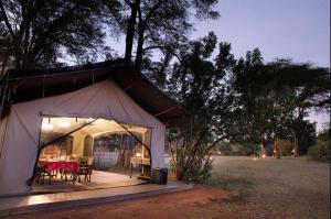a tent with tables and chairs in a field at Basecamp Adventure in Masai Mara