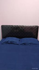 a bed with a blue pillow and a brown headboard at Varisha Homestay 2 Bedrooms, PS5, E-bike in Ngaglik +60 photos