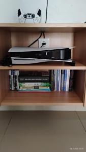 a shelf with a nintendo wii game controller and books at Varisha Homestay 2 Bedrooms, PS5, E-bike in Ngaglik