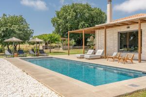 a swimming pool with chairs and a house at Alberi - Izla Homes in Skala Kefalonias