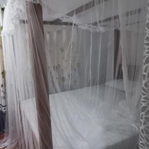 1 dormitorio con cama blanca y cortina en Sunrise Jungle Villa, en Mirissa