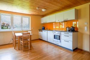 a kitchen with white cabinets and a table with chairs at Sonne Bezau - Familien- und Sporthotel Bregenzerwald in Bezau