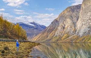 a man standing on the shore of a mountain lake at Cozy Home In Elvegard With Sauna in Elvegård +15 photos