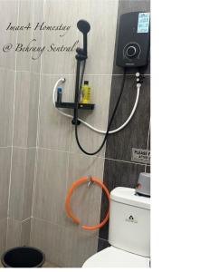 a bathroom with a toilet with an orange hose at Iman4 Homestay in Kampung Behrang