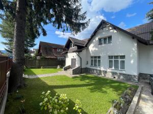 una casa blanca con un patio verde en Vila Panduri 23, en Buşteni