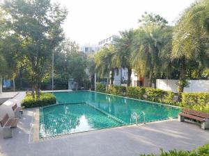 a large swimming pool with a bench and palm trees at Homestay At Foret Iconature Salaya in Sathani Wat Suwan