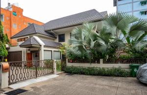 a house with a fence and a palm tree at Thonglor 25 Noble House in Bangkok