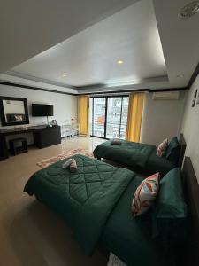 a bedroom with two green beds and a tv at Ging's Beach & Pool in Hua Hin