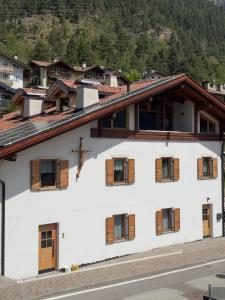 a white building with wooden windows and a mountain at Appartamenti LITEGOSA casa vacanza 3 in Panchia