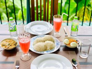 a wooden table with plates of food and drinks at Liana Guest House Ella in Ella