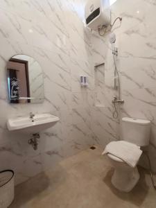 a white bathroom with a toilet and a sink at Tentram guesthouse in Waikabubak