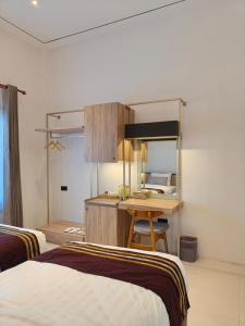 a bedroom with two beds and a desk with a mirror at Tentram guesthouse in Waikabubak