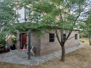 a brick house with a red door and a tree at Large house surrounded by nature in Vilanova de la Roca