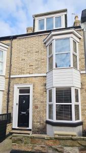 a brick house with a black door and windows at SNUZE Whitby 2 in Whitby