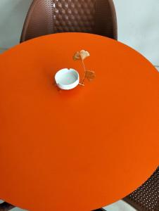 une table orange avec une tasse dessus dans l'établissement Prestige comforts, à Karachi