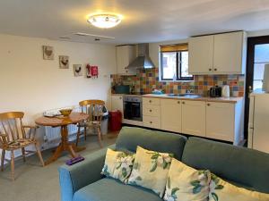 a living room with a couch and a table and a kitchen at Riscombe Farm Cottages in Exford