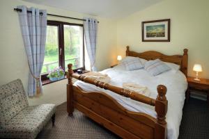 una camera da letto con un letto, una sedia e una finestra di Riscombe Farm Cottages a Exford