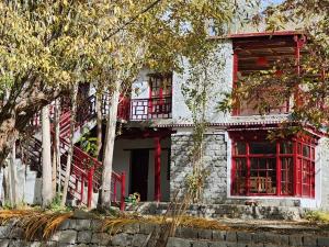 a white building with red windows and trees at Lharimo North Cottages - Nubra Valley in Wāhegaon