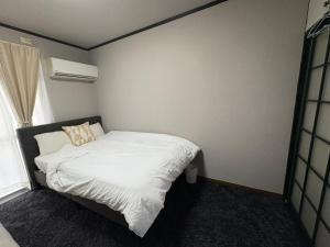 a small bedroom with a white bed and a window at 若葉コーポ103 in Fukuoka