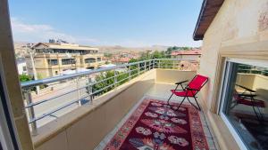 a balcony with two red chairs and a rug at Peribacası Manzaralı Modern Daire 2 in Urgup