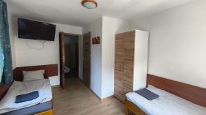 a room with two beds and a tv on the wall at Dom Narciarza in Szczyrk