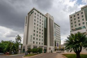 un grande edificio bianco su una strada con palme di Luxuoso Apartamento no Jade Hotel – Sofisticação e Comodidade no Coração de Brasília! a Brasilia