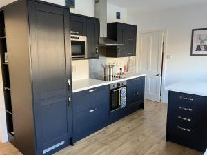 a kitchen with blue cabinets and white counter tops at Bon Accord in Fort Augustus +5 photos
