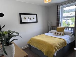 a bedroom with a bed with yellow sheets and a window at Bon Accord in Fort Augustus