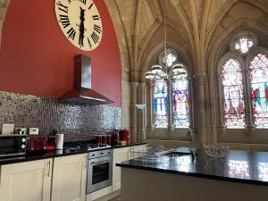 a large kitchen with a clock on the wall at St Andrew's Chapel - Abbey Church 6 in Fort Augustus +15 photos