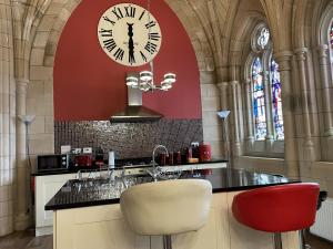 a kitchen with a clock on the wall and two chairs at St Andrew's Chapel - Abbey Church 6 in Fort Augustus