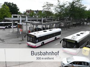 two buses are parked at a bus station at City-Apartment Germersheim in Germersheim