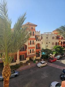 a palm tree and cars parked in front of a building at Pool & Beach Apartment in Sharm El Sheikh