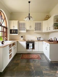a kitchen with white cabinets and a large window at Casa Miramare - Marina Beach in Southbroom
