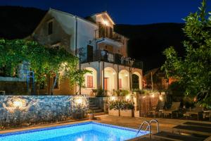 a villa with a swimming pool at night at Apartments Mezini 11 in Kotor