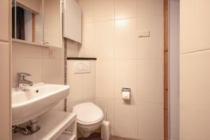 a white bathroom with a sink and a toilet at Aangenaam Texel Familie Bungalow in De Koog +57 photos
