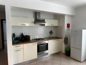 a kitchen with white cabinets and a stove and a refrigerator at Leme Bedje - By Bobbywashere in Santa Maria