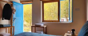 a bedroom with a blue door and a window at Lharimo North Cottages - Nubra Valley in Wāhegaon