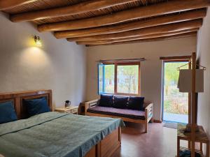 a bedroom with a bed and a couch and a window at Lharimo North Cottages - Nubra Valley in Wāhegaon