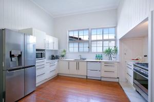 a kitchen with white cabinets and a stainless steel refrigerator at Central Haven Milton 4BR Sleeps 10 in Brisbane