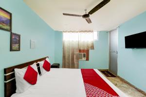 Un dormitorio con una cama con almohadas rojas y un televisor en Hotel O 27 Degree Hotel, en Dhanbād 21 fotos más