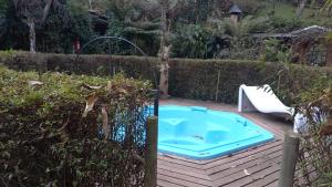 a hot tub in a garden next to a fence at Pousada Di Oliva in Campos do Jordão