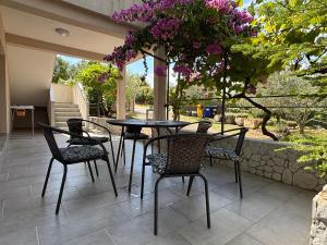 a table and chairs on a patio with purple flowers at NEW Apartment Ema II in Vrh