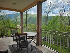 a table and chairs on a balcony with a view of the mountains at Give Peace a Chance - 10 km from Sarajevo City Center in Petrovići