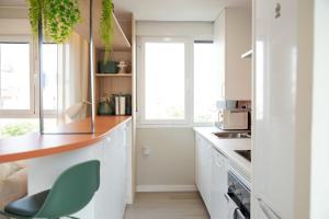 a kitchen with white cabinets and a green chair at Zabella Ossau - Nuevo ático a estrenar en el tubo in Zaragoza